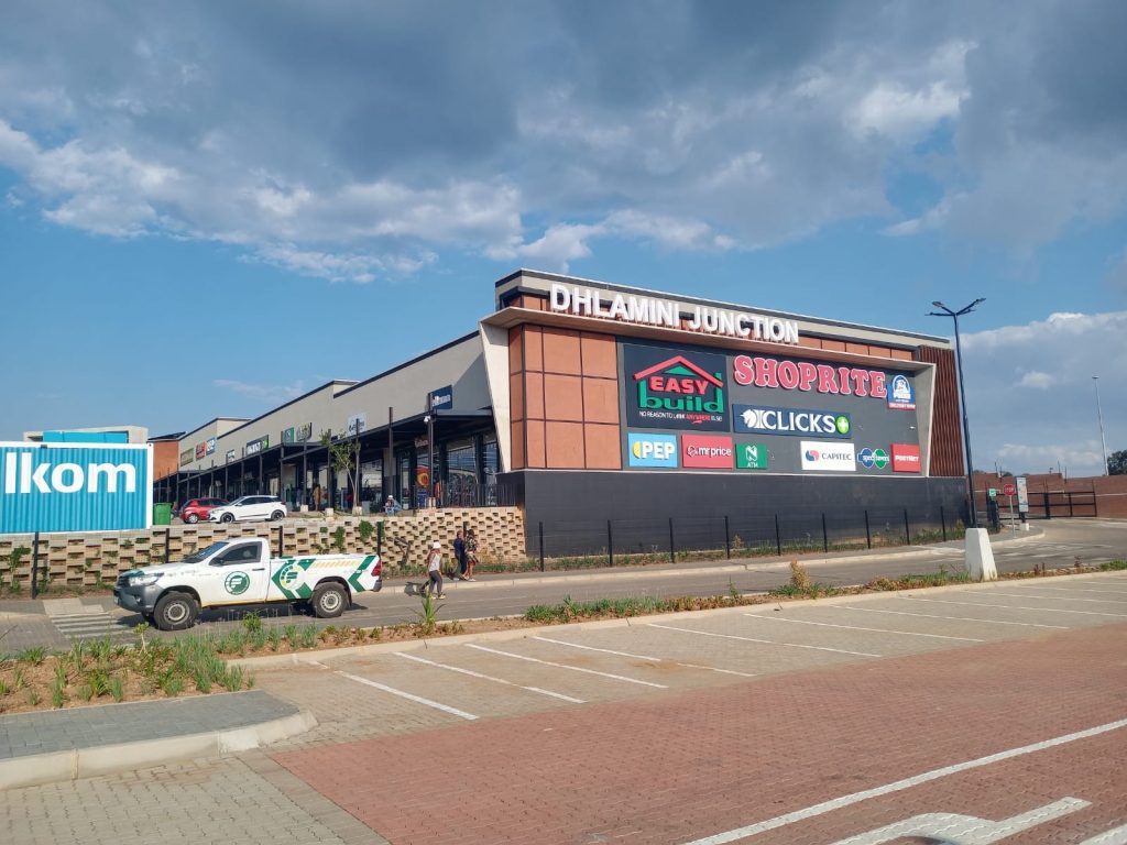 Side view of Dhlamini Junction shopping centre showing external signage and parking