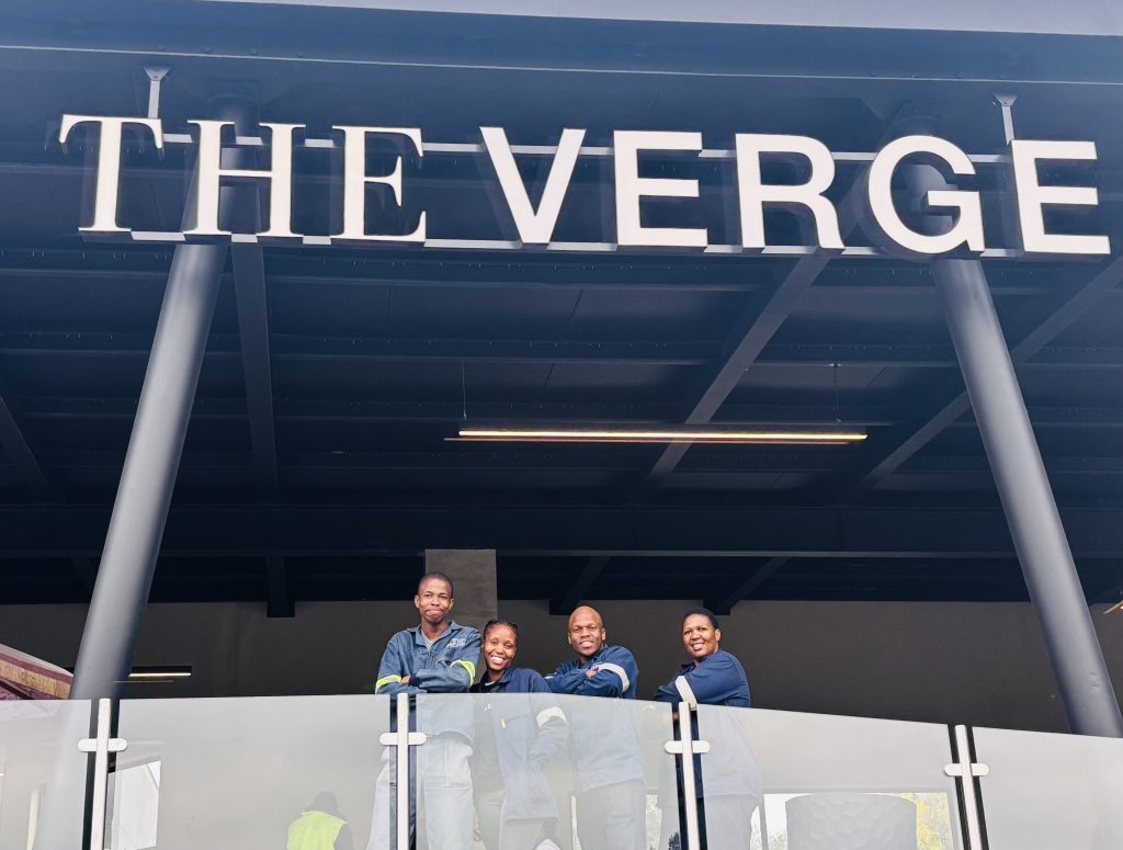 Faradays Electrical apprentices standing under The Verge signage.