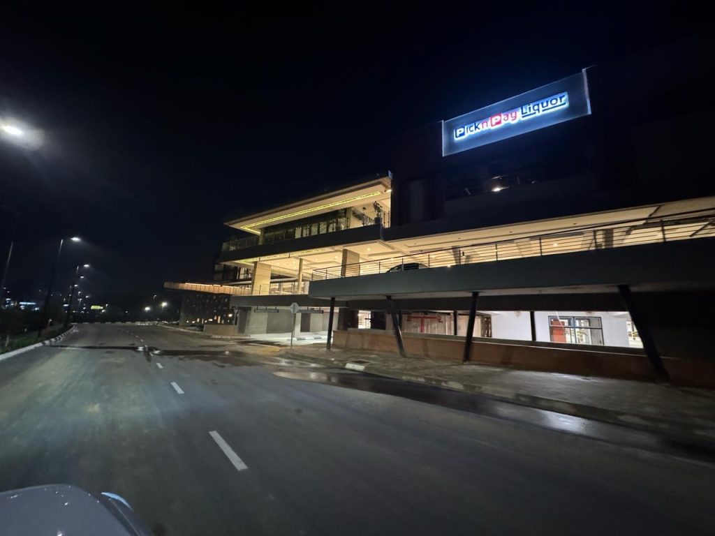 Wide night shot of The Verge Shopping Centre with full exterior illumination.