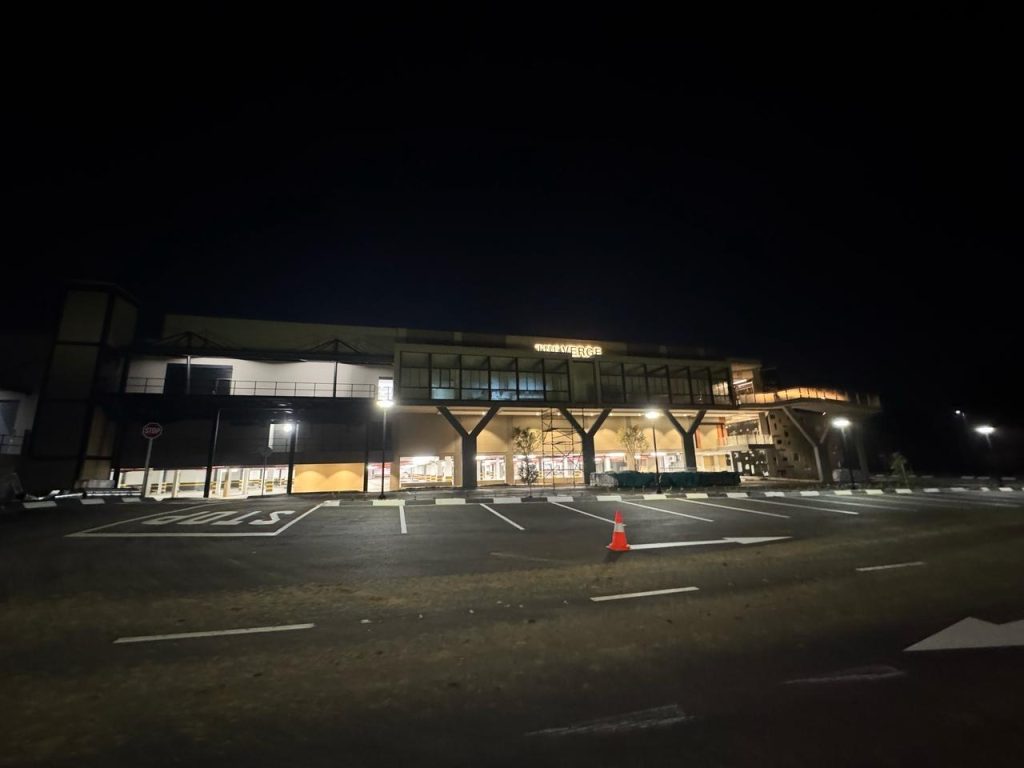 Nighttime view of storefronts and signage at The Verge Shopping Centre.